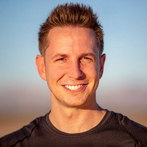 Matthew McWilliam, smiling, with a desert sunset behind him